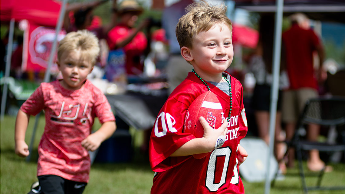 Kids in JSU jerseys play football during a homecoming tailgate party