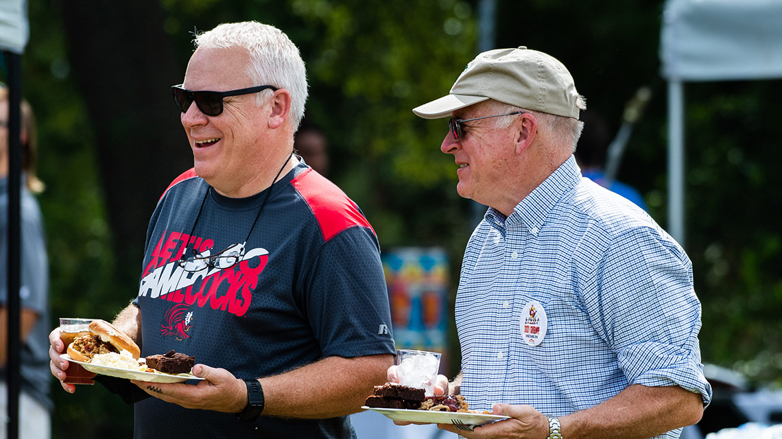 Alumni fill their plates with barbecue during the tailgate party