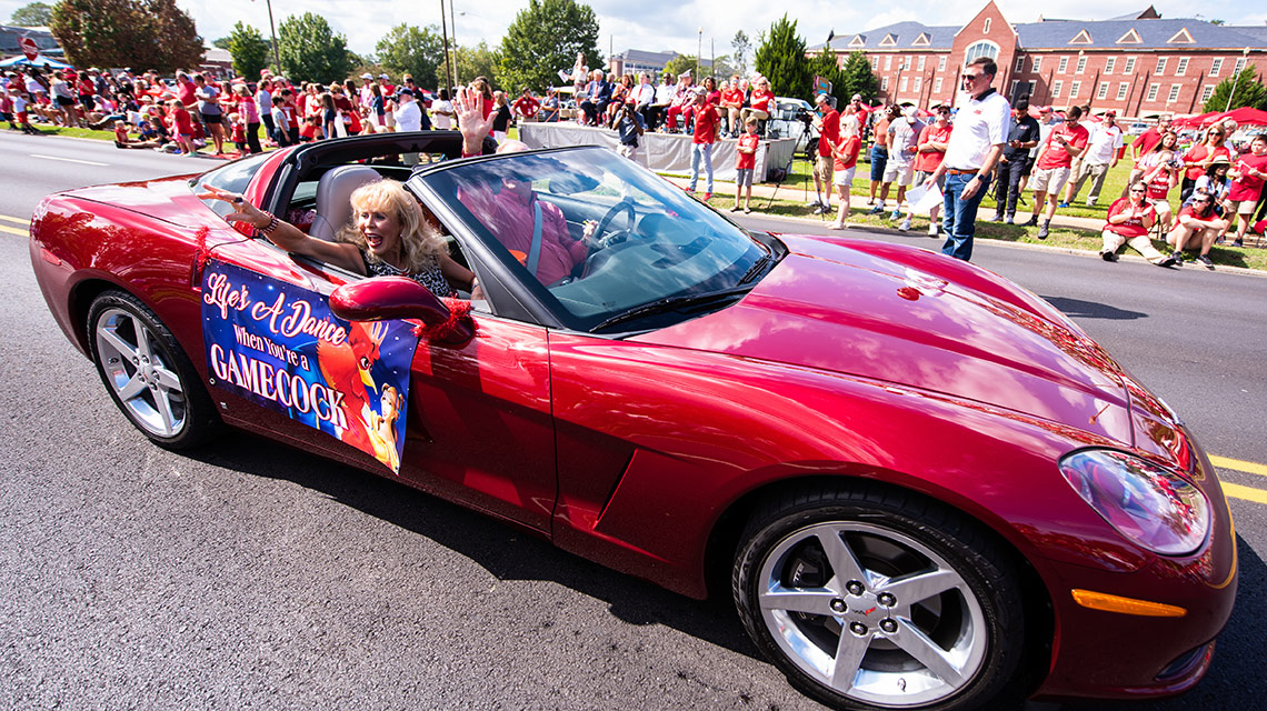 Ken and Jenny Howell drive their red convertible car in the parade