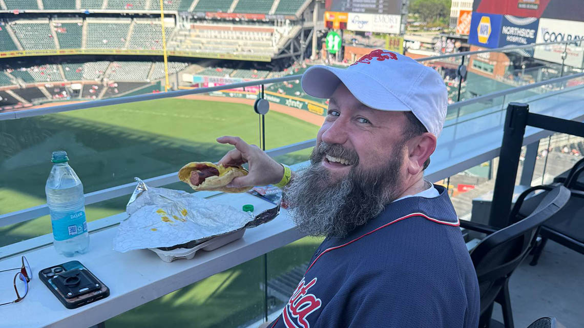 An alum enjoying a hot dog before the game