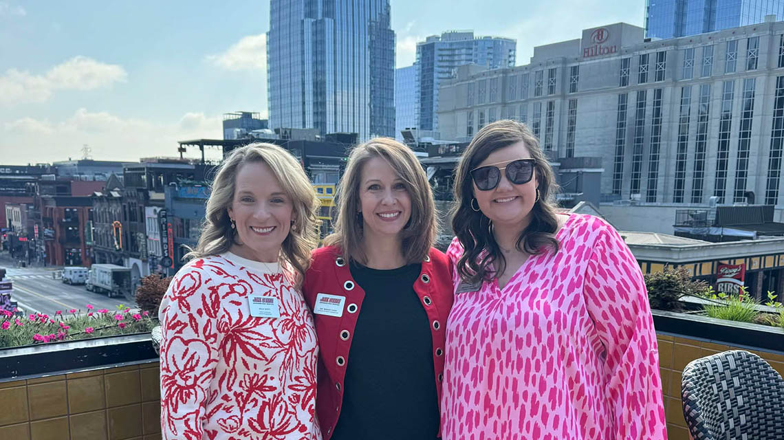 Our alumni staff in Nashville pose with the city skyline