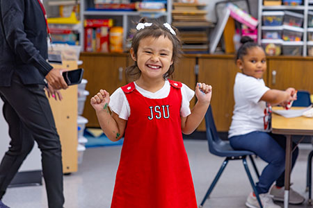 A student in the prek classroom smiles for a photo