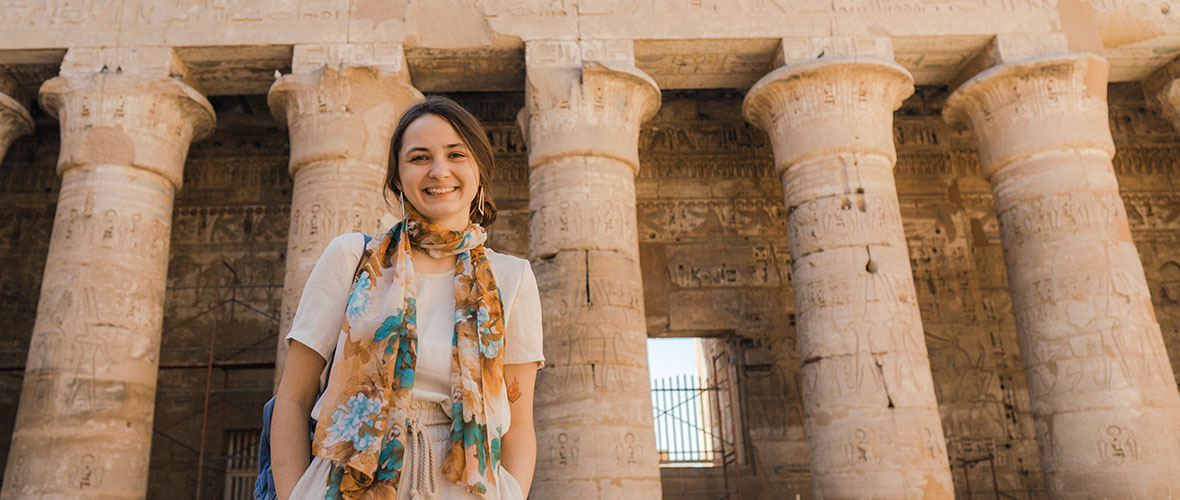 A female student stands on the steps of the temple at Luxor