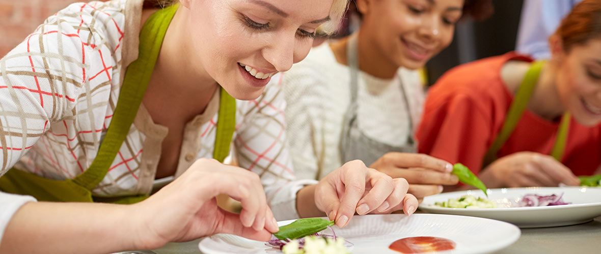 A student carefully arranges a garnish on a plate