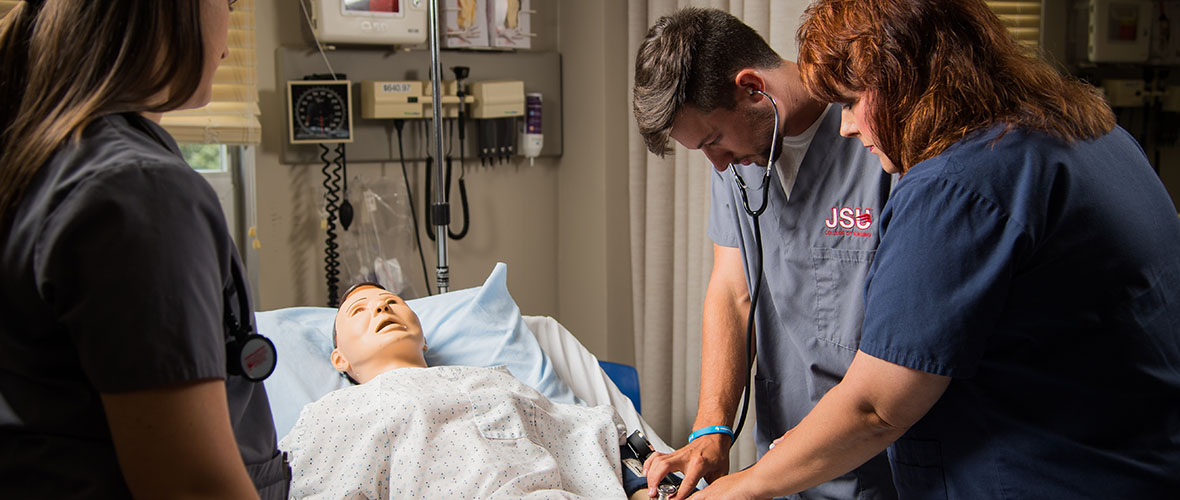 Nursing students practicing on a simulation patient
