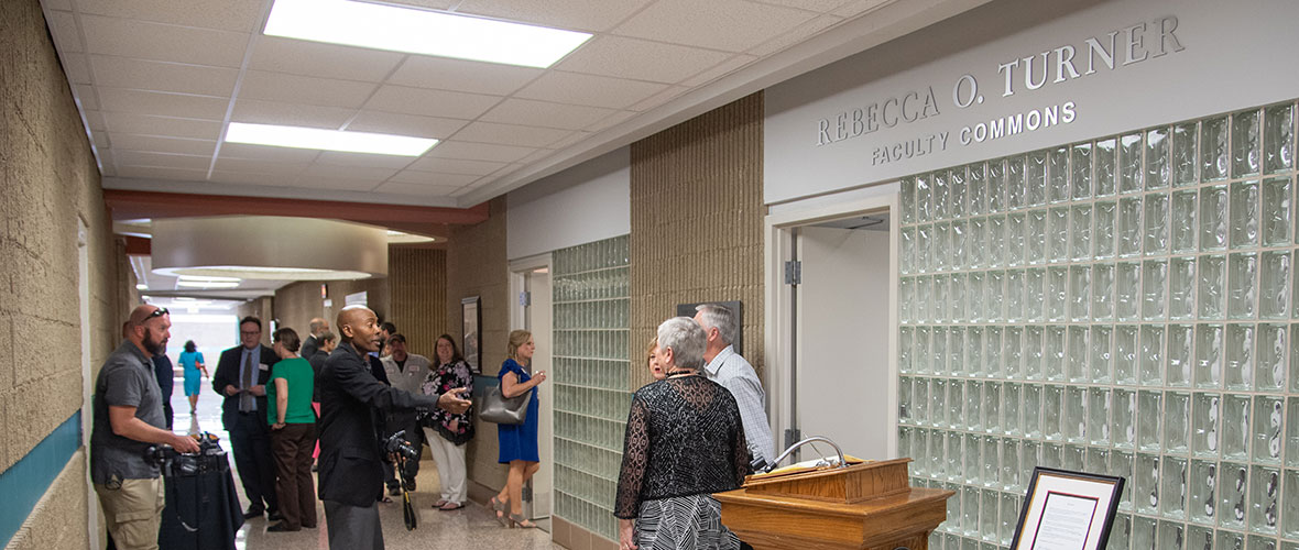 Faculty and staff gather outside the door to the Rebecca O Turner Faculty Commons to show their support at its dedication. In the doorway are Dr. Turner and President Meehan.