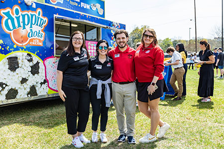 Students holding up fear the beak sign outside of library