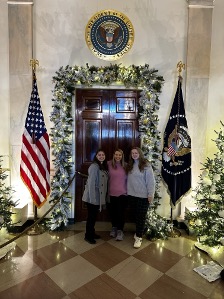 Hannah McTenn Bock, Reanna Medders, and Adyson Merchant beneath the Presidential Seal in the White House 