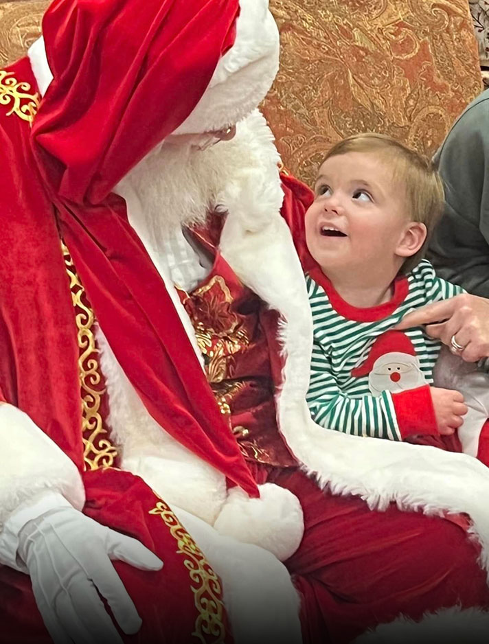 A young boy sits on Santa's lap at Christmas at the Canyon 2023.