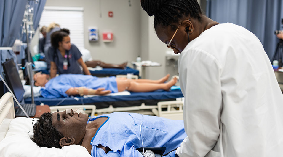 nursing students examining 'patient' in lab