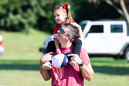 A parents holding daughter on his shoulders