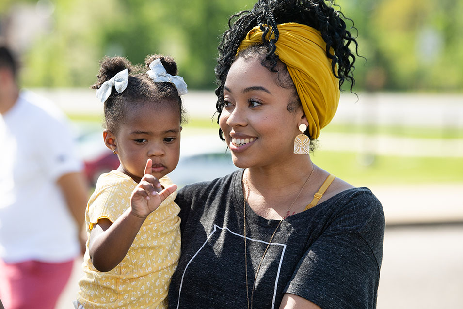 An adult learner holding her child