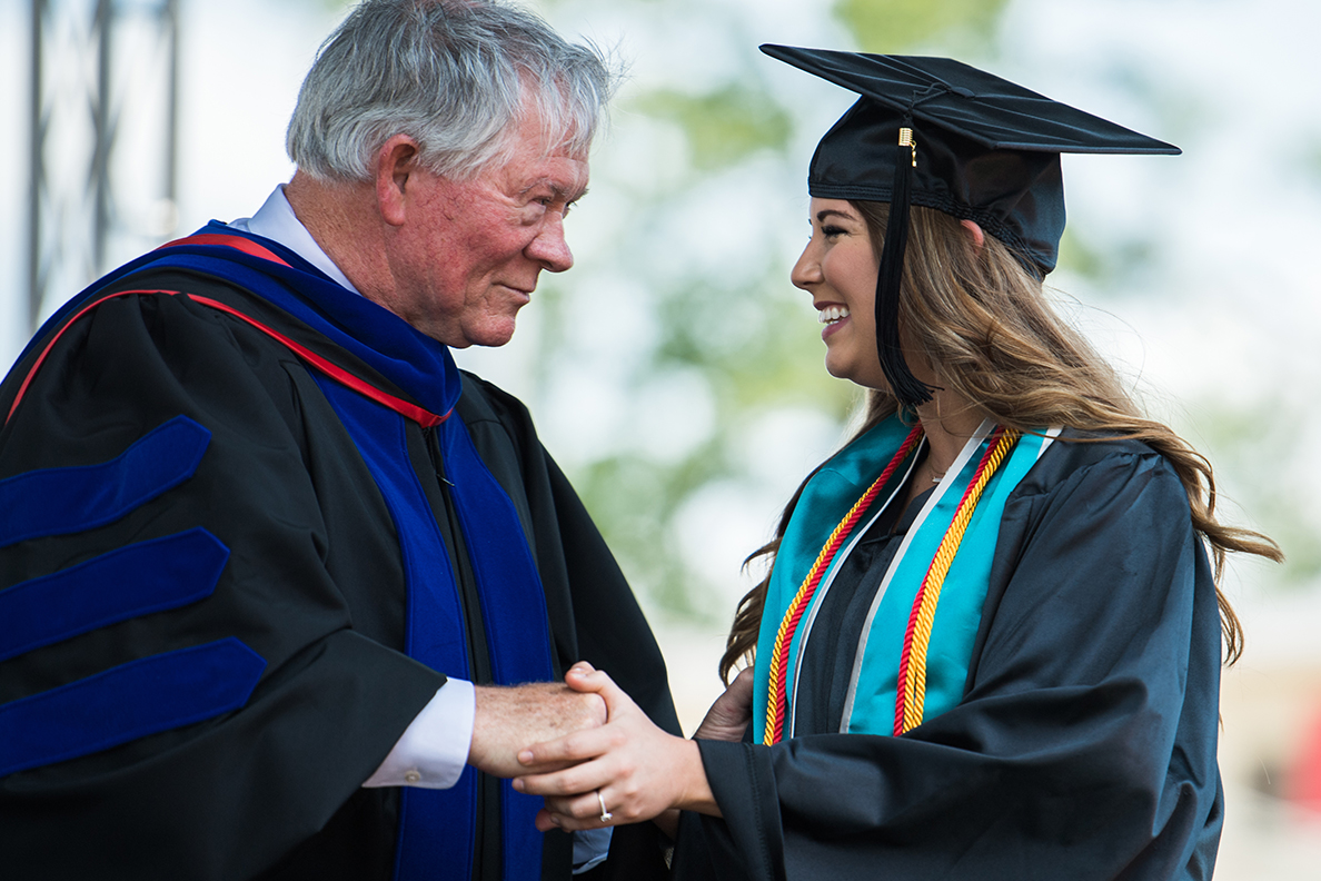 Doctor Tommy Turner congratulates a graduate at spring commencement