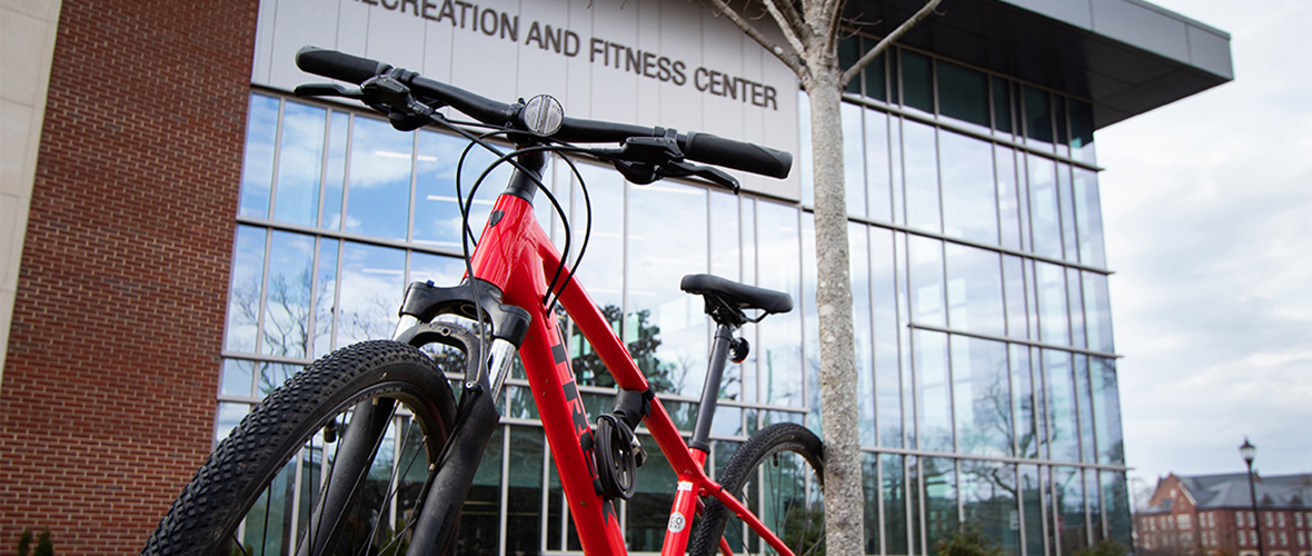 A red bike leaning against a tree outside the Recreation and Fitness Center