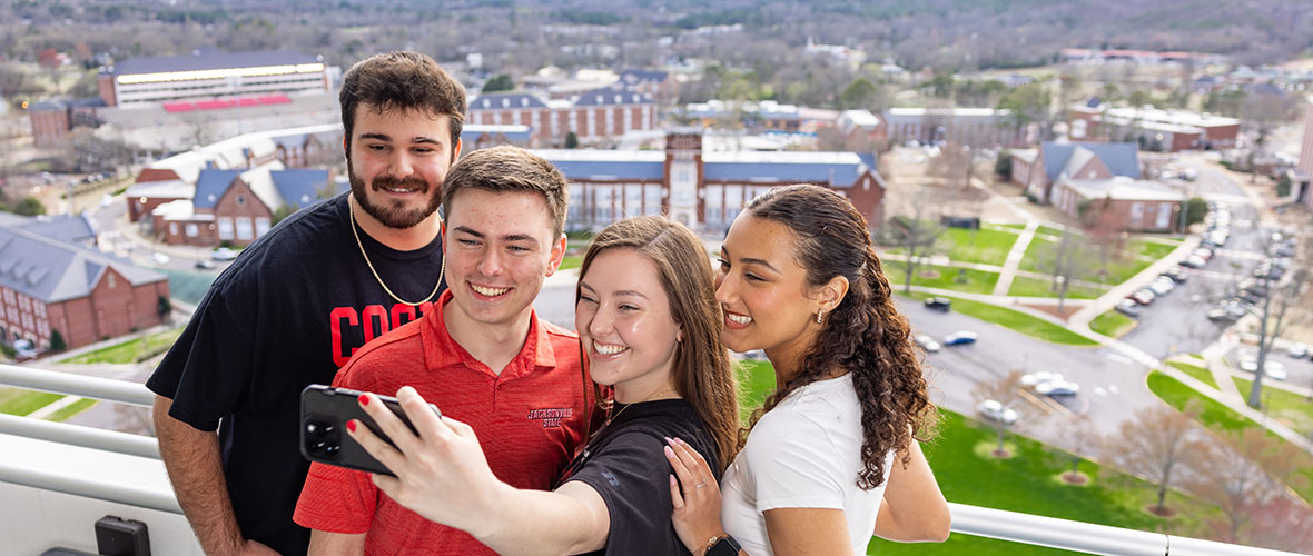 Three JSU Ambassadors on Houston Cole Library observation deck, with a view of the west side of campus behind them.